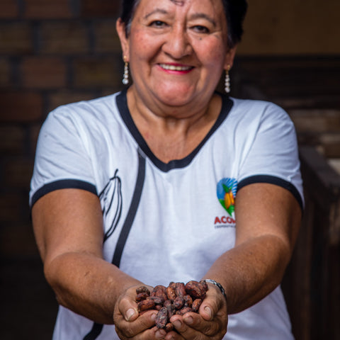 cacao farmer from ACOPAGRO co-op in Peru smiling and holding a handful of cocoa beans