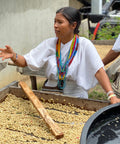 woman coffee farmer of Anei cooperative talking in front of depulped green coffee beans in Colombia