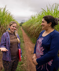 Equal Exchange's Laura Bechard visits with Manduvira sugar producer standing on a dirt road between two sugarcane fields