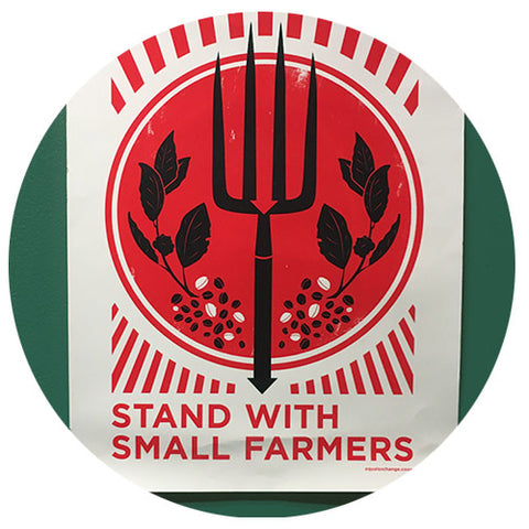 Red and white graphic poster that says stand with small farmers on a green wall