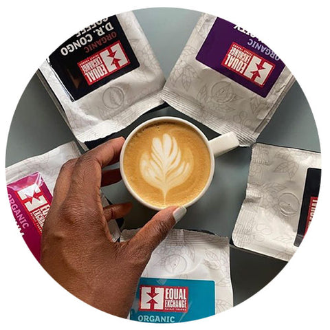 hand reaching for an espresso drink in the center of a circle surrounded by radiating Equal Exchange coffee bags