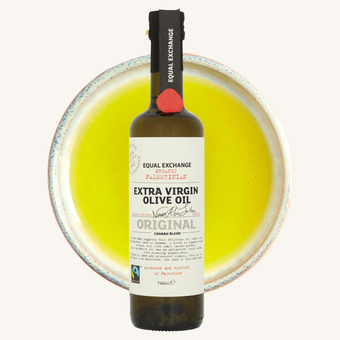 bottle of Equal Exchange olive oil over a bowl of olive oil in background